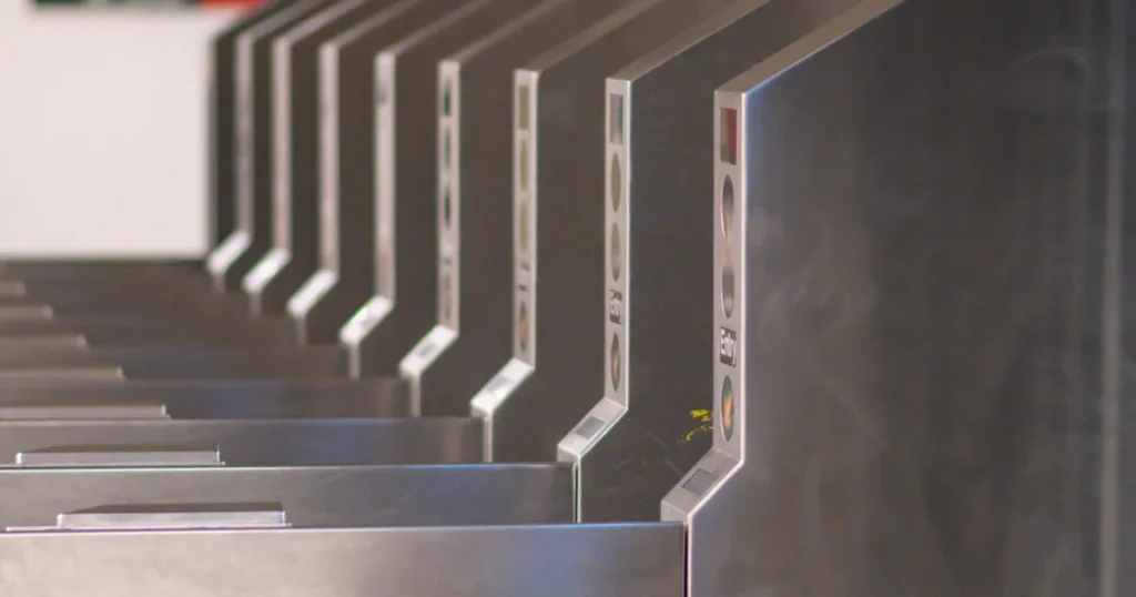 Row of stainless steel ticket gates with entry signals, seen in close-up