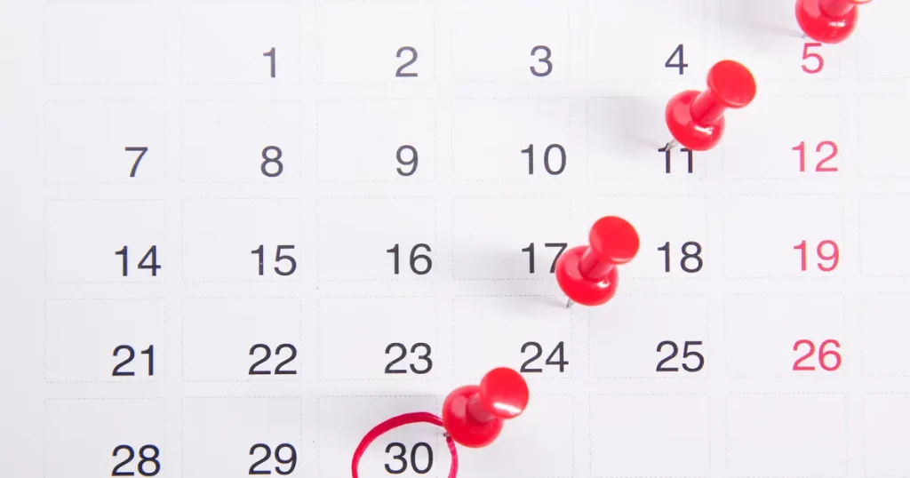 Calendar with red pins marking dates, illustrating Google Ads policy news and enforcement dates