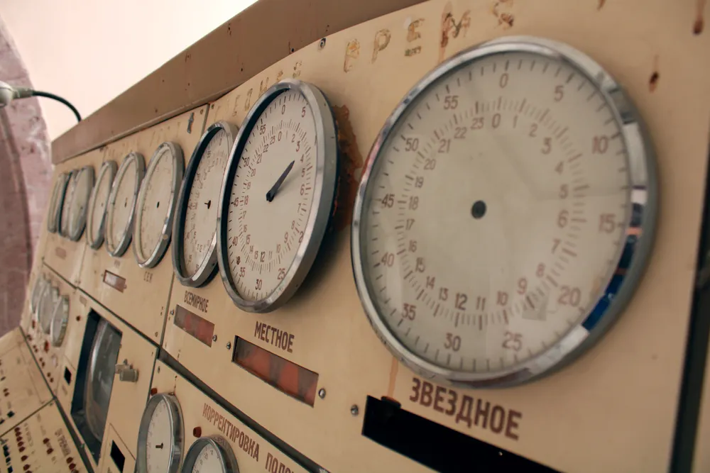 Row of analog gauges and dials on a vintage control panel, seen at an angle