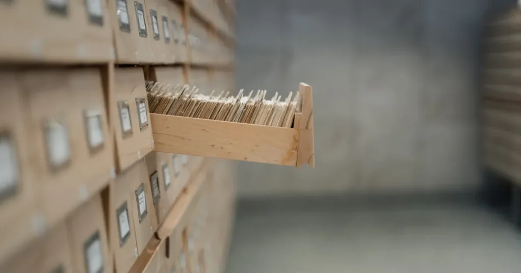 One wooden card catalog drawer pulled open from a wall of labelled record drawers